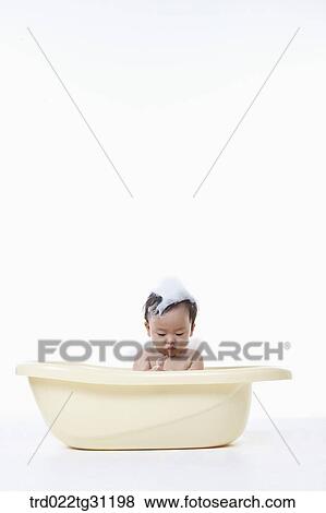 Stock Photo - A baby taking a bath in the bathtub with the bubble on his body. Fotosearch