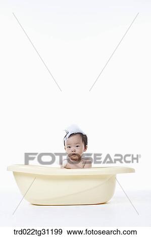 Stock Photo - A baby taking a bath in the bathtub with the bubble on his body. Fotosearch