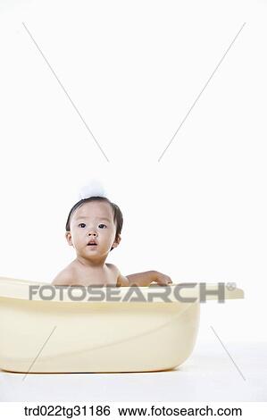 Stock Photograph - A baby taking a bath in the bathtub with the bubble on his head. Fotosearch