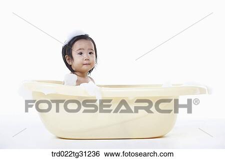 Stock Photograph - A baby taking a bath in the bathtub with the bubble on her body. Fotosearch