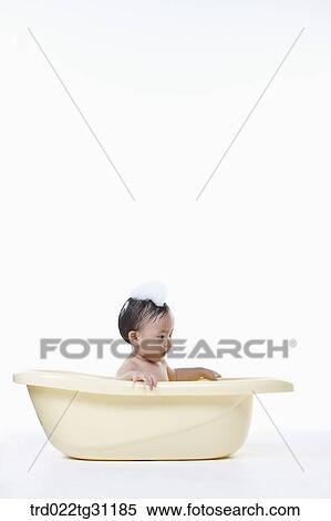 Stock Photography - A baby taking a bath in the bathtub with the bubble on his head. Fotosearch