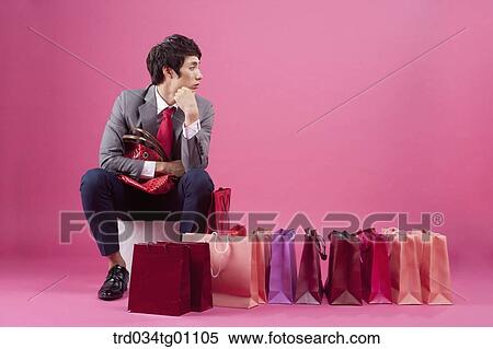 A bored man having a purse with many shopping bags around View Large Photo Image Stock Photography - A bored man having a purse with many shopping bags around. Fotosearch