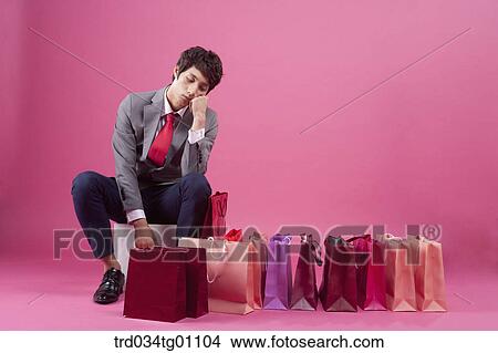 Picture - A bored man with many shopping bags around. Fotosearch