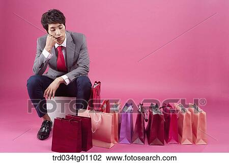 Stock Image - A bored man with many shopping bags around. Fotosearch