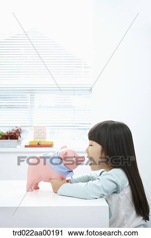 A girl facing a pink piggy bank View Large Photo Image Stock Image - A girl facing a pink piggy bank. Fotosearch