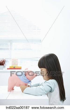 Stock Photo - A girl facing a pink piggy bank. Fotosearch