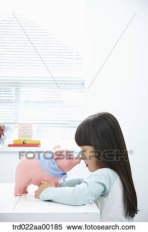 A girl facing a pink piggy bank View Large Photo Image Stock Photography - A girl facing a pink piggy bank. Fotosearch
