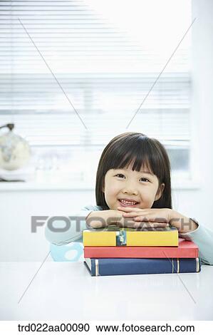 Stock Image - A girl having her hands on the pile of books. Fotosearch