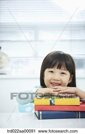 Stock Image - A girl having her hands on the pile of books. Fotosearch