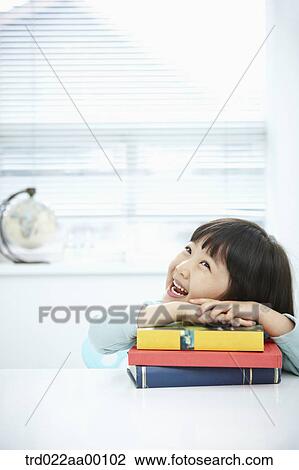 Stock Image - A girl having her hands on the pile of books. Fotosearch