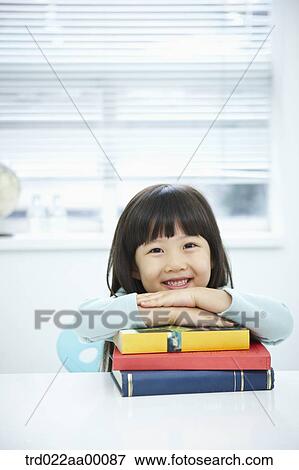 Stock Photo - A girl having her hands on the pile of books. Fotosearch