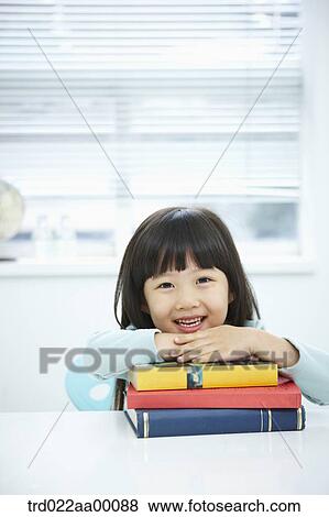 Stock Photo - A girl having her hands on the pile of books. Fotosearch
