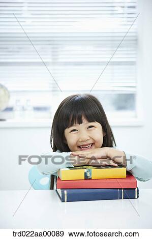 Stock Photo - A girl having her hands on the pile of books. Fotosearch