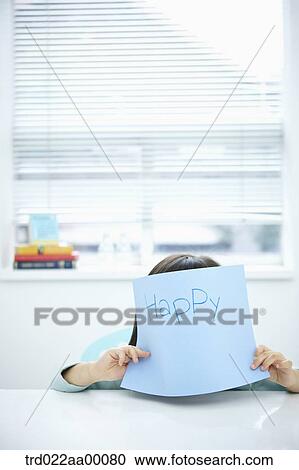Stock Image - A girl hiding her face with blue paper 'I'm happy'. Fotosearch
