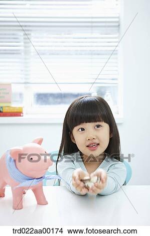 A girl holding coin in her hands with a pink piggy bank View Large Photo Image Picture - A girl holding coin in her hands with a pink piggy bank . Fotosearch