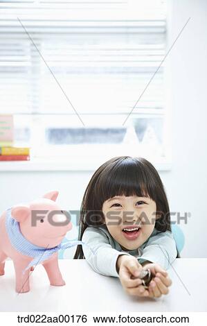 Stock Photograph - A girl holding coin in her hands with a pink piggy bank . Fotosearch