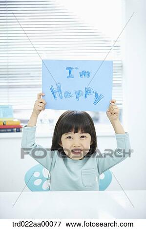 Stock Photo - A girl holding up blue paper with 'I'm happy'. Fotosearch
