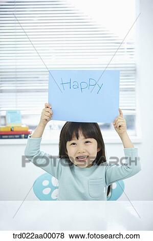 Stock Photo - A girl holding up blue paper with 'I'm happy'. Fotosearch