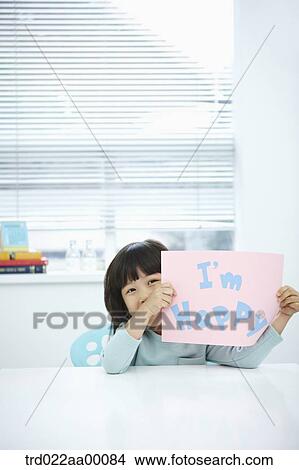 Picture - A girl holding up pink paper with 'I'm happy'. Fotosearch