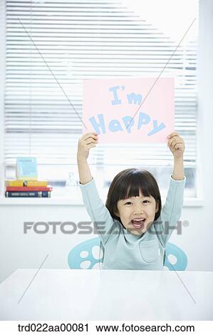 Stock Image - A girl holding up pink paper with 'I'm happy'. Fotosearch