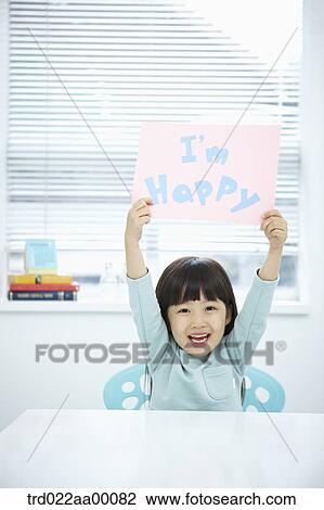 Stock Image - A girl holding up pink paper with 'I'm happy'. Fotosearch