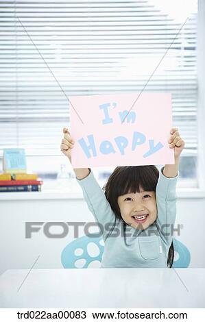 Stock Image - A girl holding up pink paper with 'I'm happy'. Fotosearch