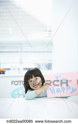 Stock Photography - A girl holding up pink paper with 'I'm happy'. Fotosearch