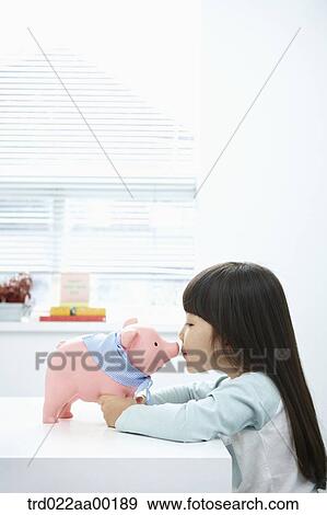 Stock Photo - A girl kissing a pink piggy bank. Fotosearch