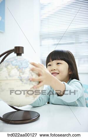 Stock Photo - A girl looking a globe with her hand on it. Fotosearch