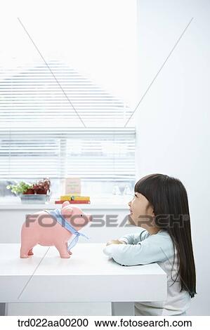 A girl looking at a pink piggy bank View Large Photo Image Stock Image - A girl looking at a pink piggy bank. Fotosearch