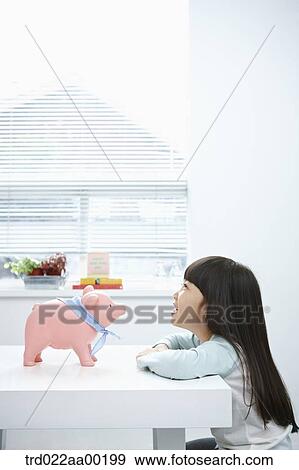 A girl looking at a pink piggy bank View Large Photo Image Stock Photo - A girl looking at a pink piggy bank. Fotosearch
