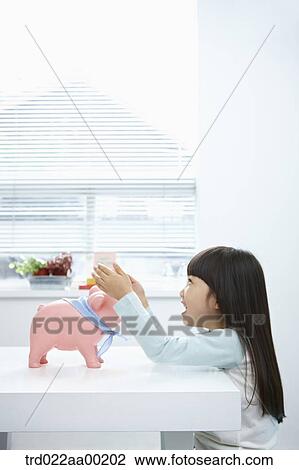 A girl putting her hands around a pink piggy bank View Large Photo Image Stock Image - A girl putting her hands around a pink piggy bank. Fotosearch