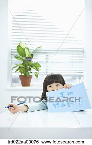 Stock Photograph - A girl showing blue paper with 'I'm happy' with a pencil in her hand. Fotosearch