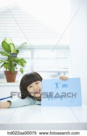 Stock Photography - A girl showing blue paper with 'I'm happy' with a pencil in her hand. Fotosearch