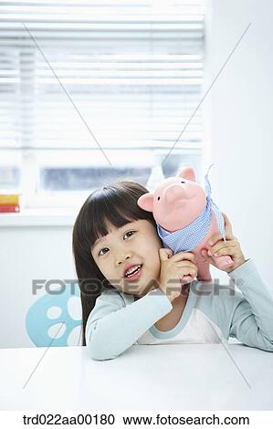 Stock Image - A girl with a pink piggy bank on her face. Fotosearch