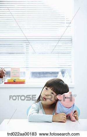 Stock Image - A girl with a pink piggy bank on her face. Fotosearch