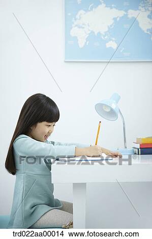 A girl writing on a book in front of the desk View Large Photo Image Picture - A girl writing on a book in front of the desk. Fotosearch