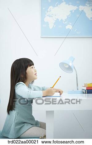 A girl writing on a book in front of the desk View Large Photo Image Stock Image - A girl writing on a book in front of the desk. Fotosearch