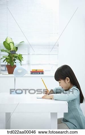 A girl writing on a book in front of the desk View Large Photo Image Stock Photograph - A girl writing on a book in front of the desk. Fotosearch