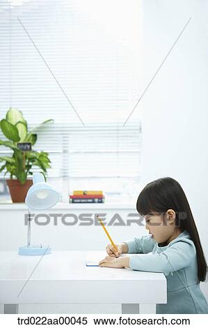 A girl writing on a book in front of the desk View Large Photo Image Stock Photography - A girl writing on a book in front of the desk. Fotosearch