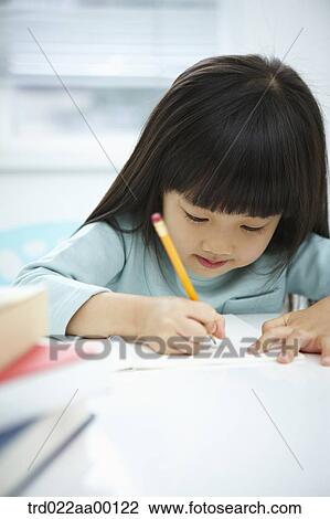 Stock Image - A girl writing on a notebook with a pencil . Fotosearch