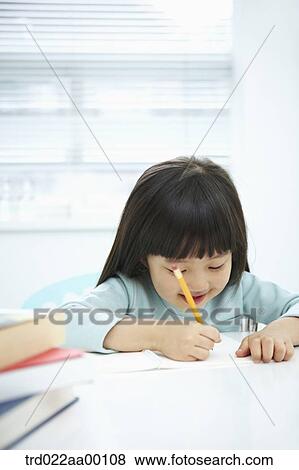 Stock Photo - A girl writing on a notebook with a pencil . Fotosearch