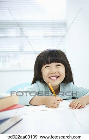 A girl writing on a notebook with a pencil View Large Photo Image Stock Photo - A girl writing on a notebook with a pencil . Fotosearch