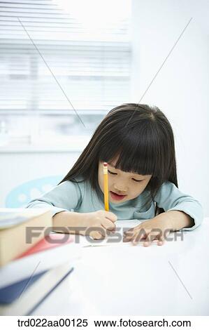 Stock Photography - A girl writing on a notebook with a pencil . Fotosearch