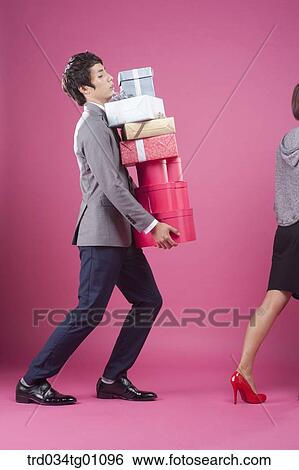 A man following a woman with the piled gift boxes on his hand View Large Photo Image Stock Photograph - A man following a woman with the piled gift boxes on his hand . Fotosearch