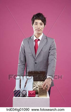 A man having his hand on the gift box with the shopping bag and fashion item around View Large Photo Image Stock Image - A man having his hand on the gift box with the shopping bag and fashion item around. Fotosearch