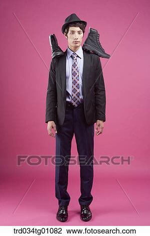 Stock Image - A man having the black sneakers on his shoulders. Fotosearch