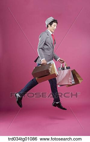 Stock Photograph - A man jumping with the many shopping bags. Fotosearch