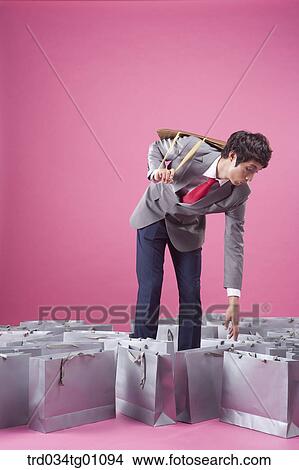 A man picking up one of gray shopping bags View Large Photo Image Picture - A man picking up one of gray shopping bags. Fotosearch