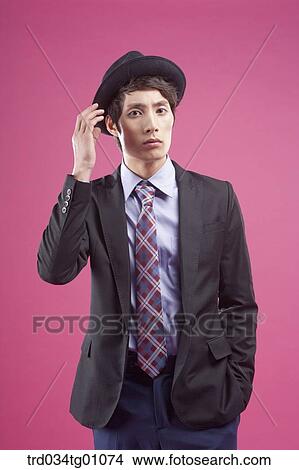 A man wearing black hat and suit with his hand touching his hat View Large Photo Image Picture - A man wearing black hat and suit with his hand touching his hat . Fotosearch